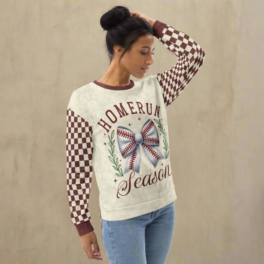 Woman wearing a sweater with 'Homerun Season' text and checkered sleeves against a beige background