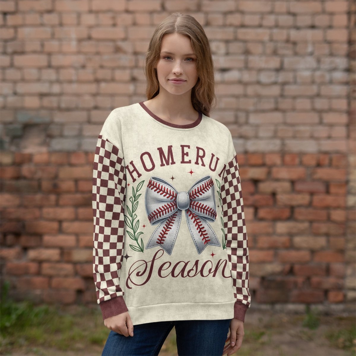 Woman wearing a sweater with 'Homerun Season' design against a brick wall.