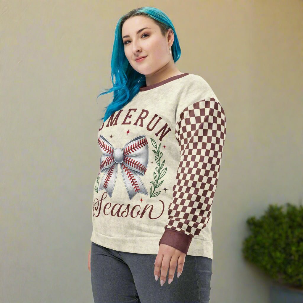 Person wearing a sweater with a baseball and bow design on a neutral background