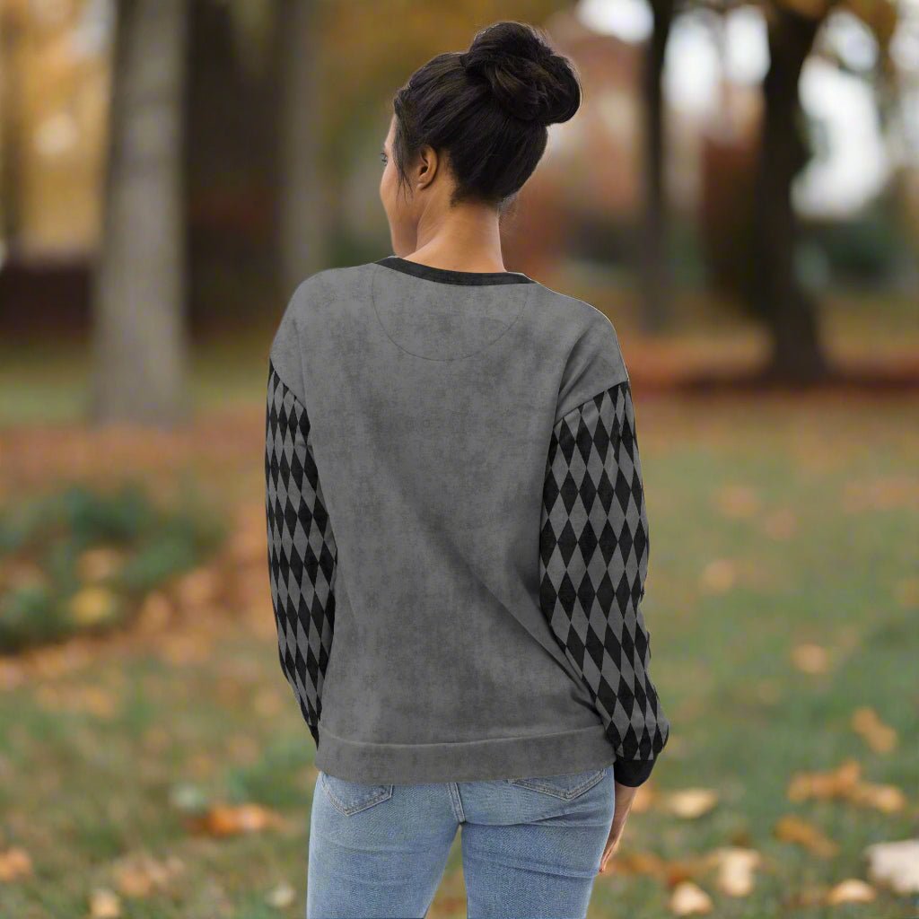 Person wearing a gray sweater with black and gray checkered sleeves outdoors