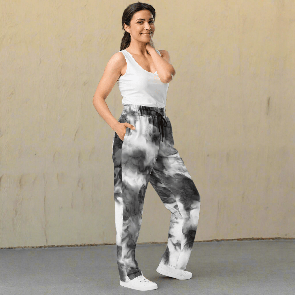 Woman wearing tie-dye pants and a white top on a neutral background