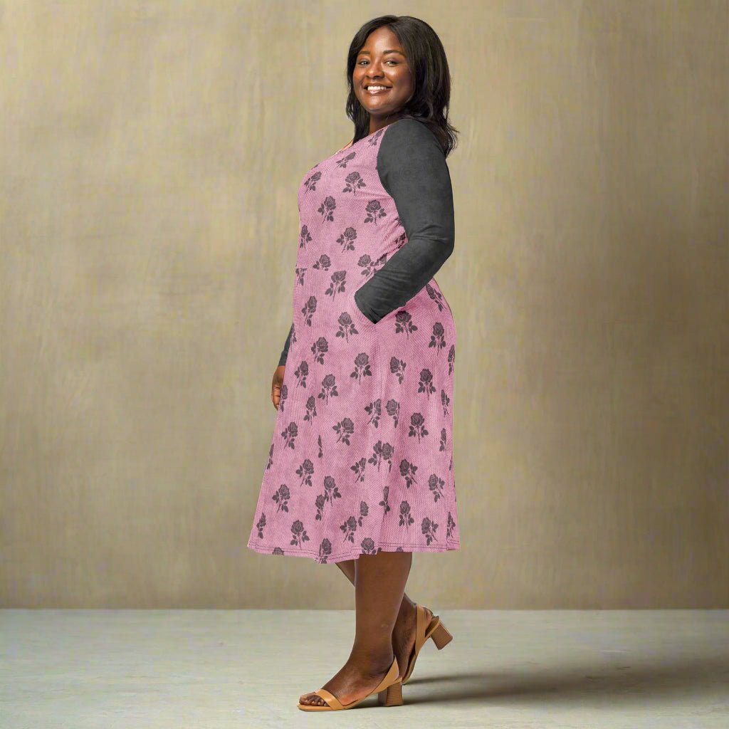 Woman wearing a pink floral dress with gray sleeves on a neutral background
