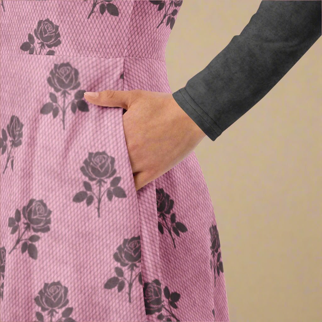 Pink dress with black rose pattern worn by a person with a gray sleeve.