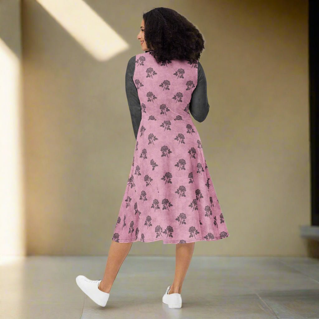 Woman wearing a pink dress with charcoal floral pattern with beige walls.