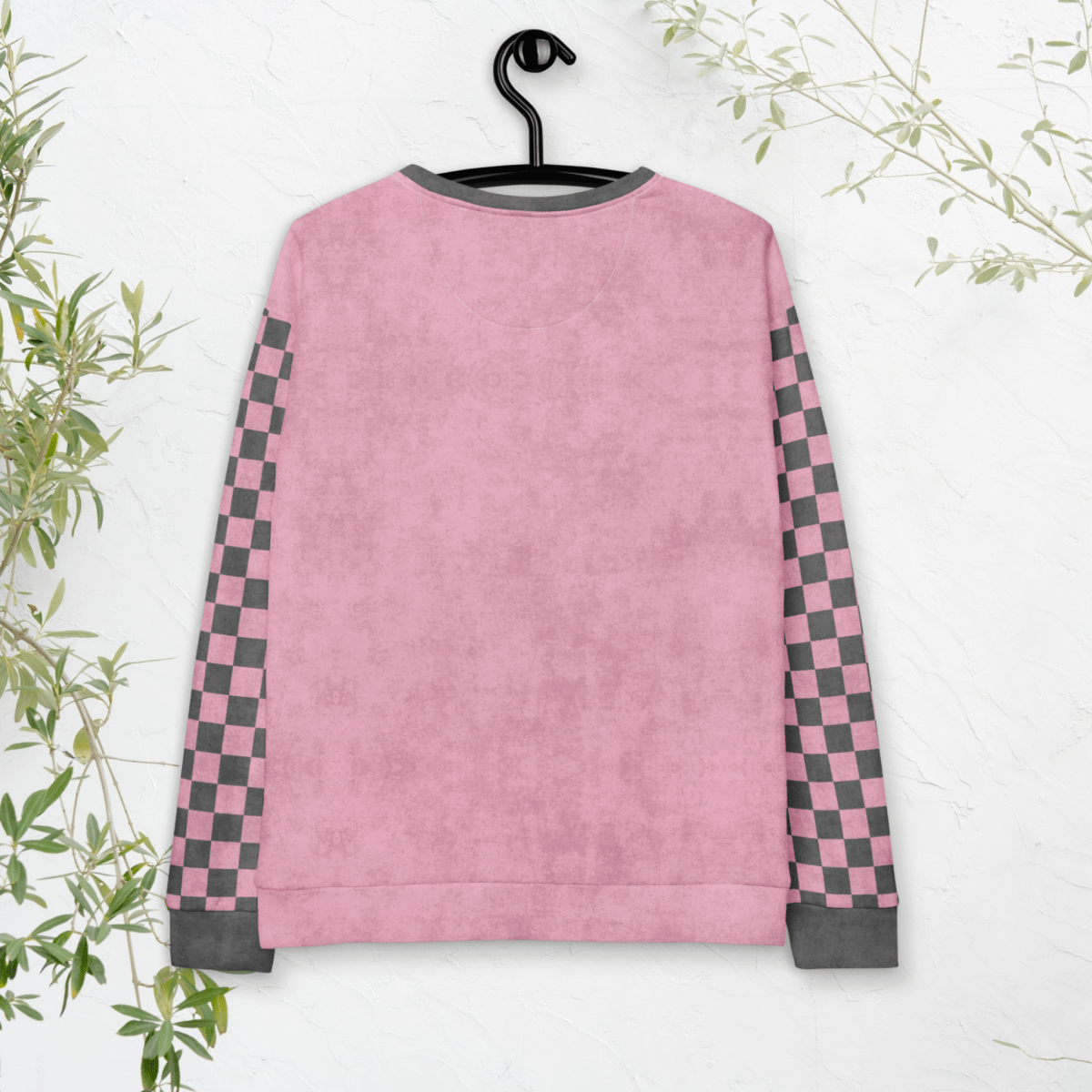 Pink sweatshirt with checkered sleeves on a hanger against a white background
