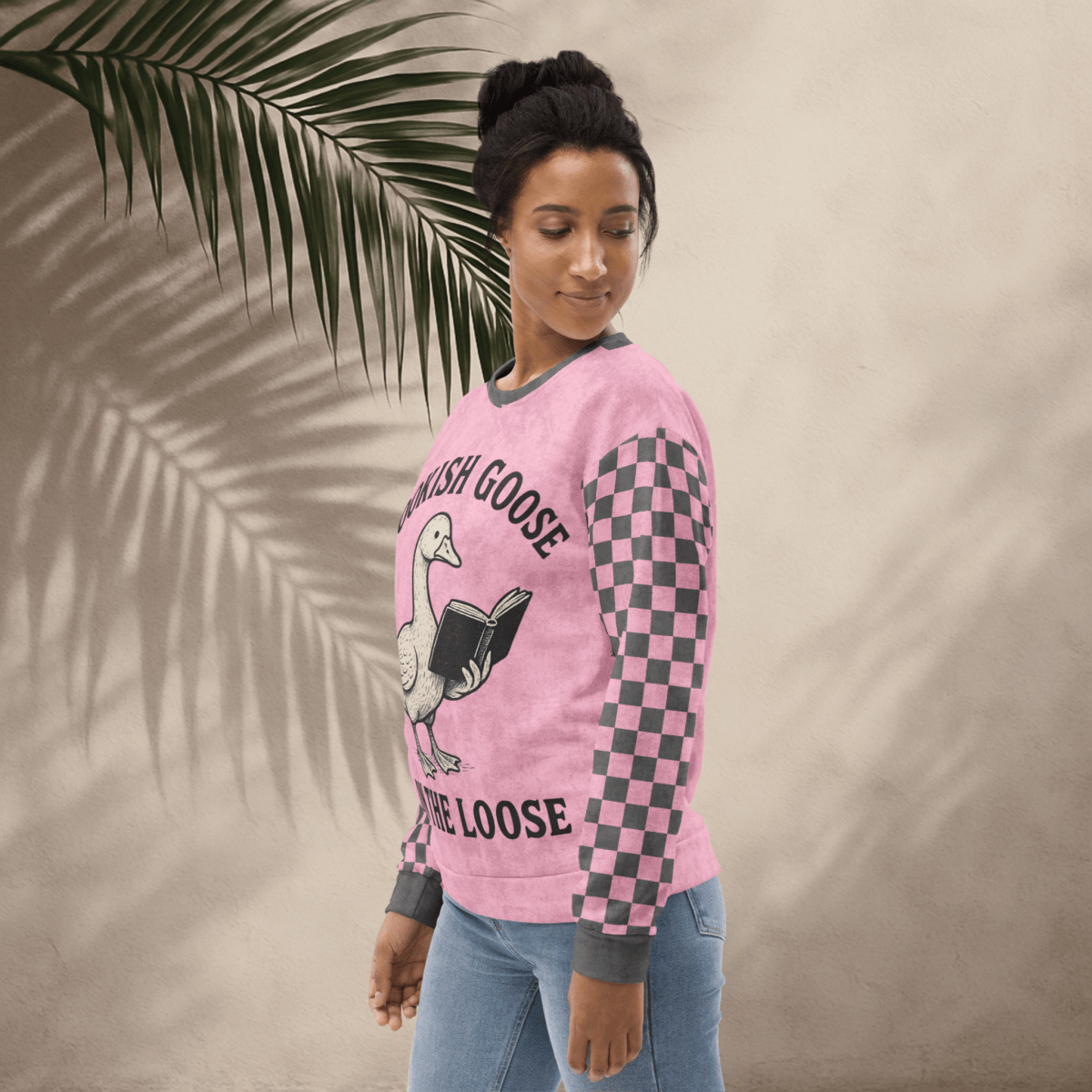 Person wearing a pink long-sleeve shirt with a graphic design on a beige background