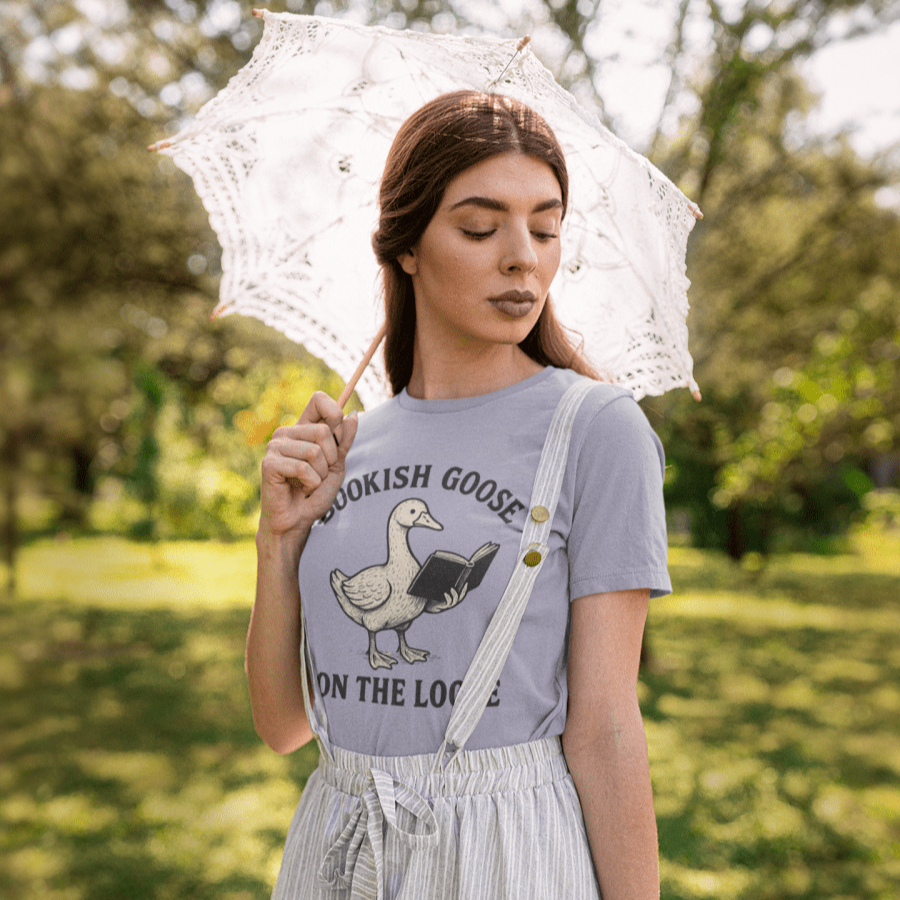 Woman holding a transparent umbrella in a park wearing a graphic t-shirt and overalls.