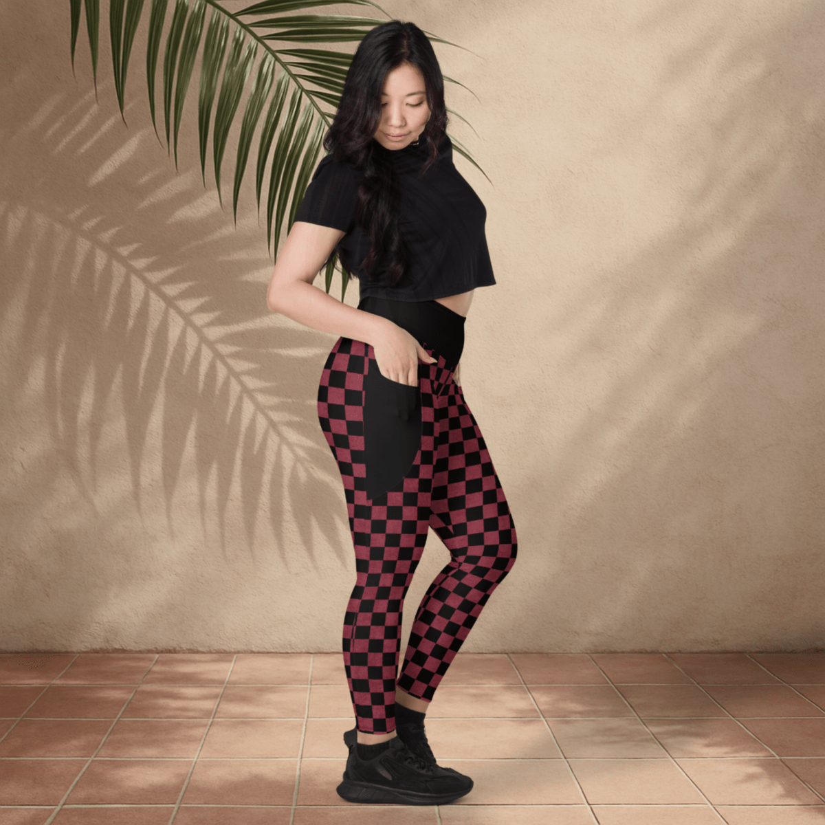 Woman wearing black and burgundy checkered pants with a plain background