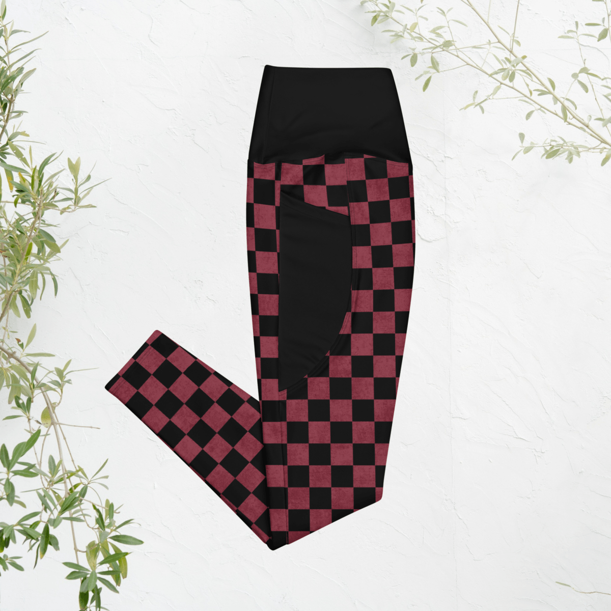 Black and burgundy checkered leggings on a white background with green leaves.