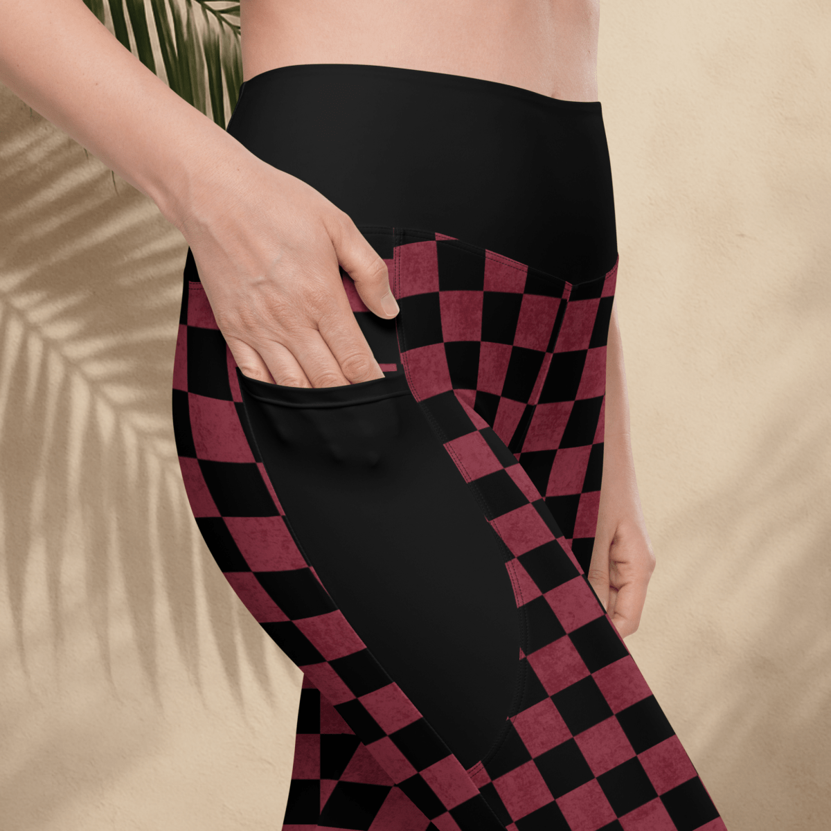 Person wearing black and burgundy checkered leggings on a beige background