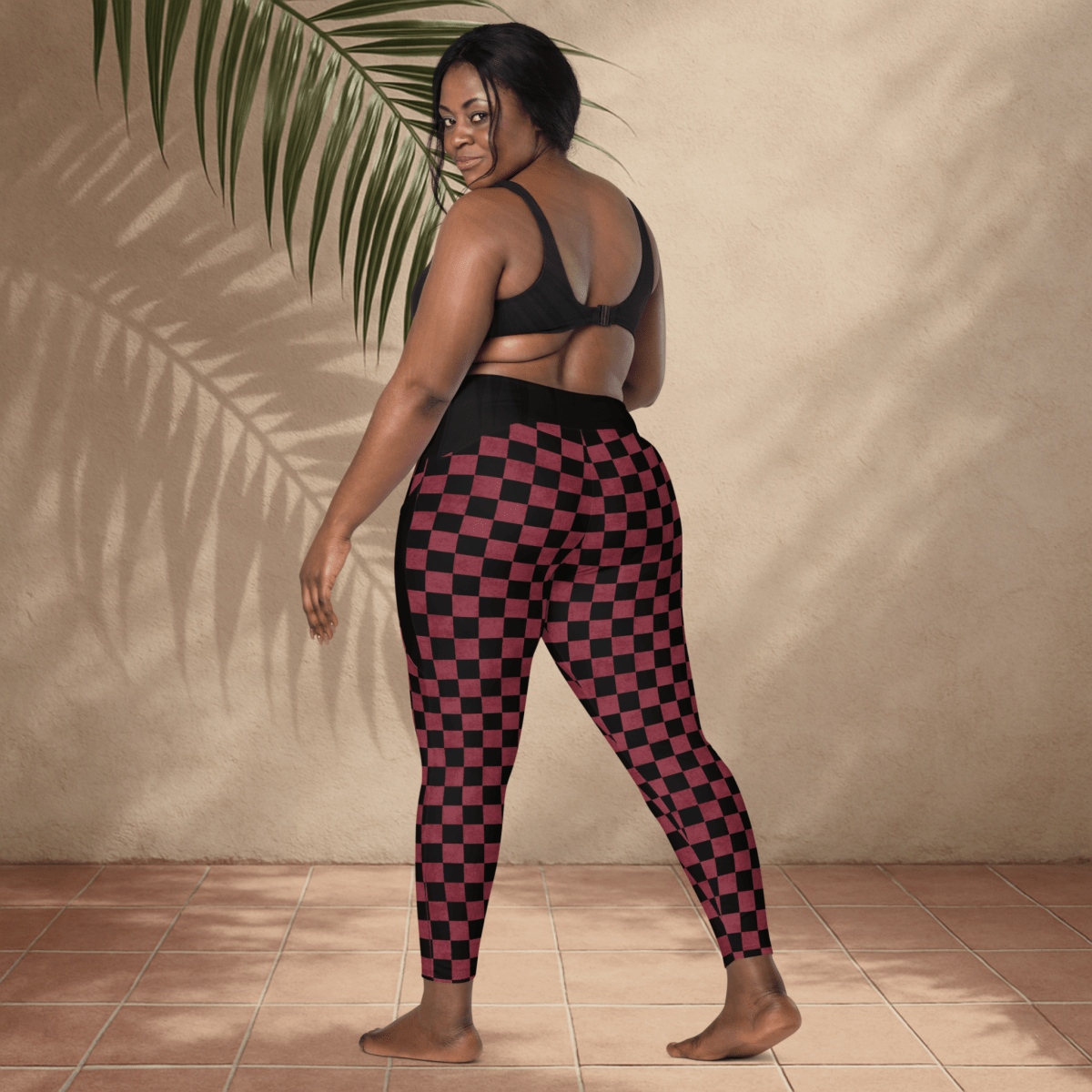 Person wearing black and burgundy checkered leggings against a beige wall.