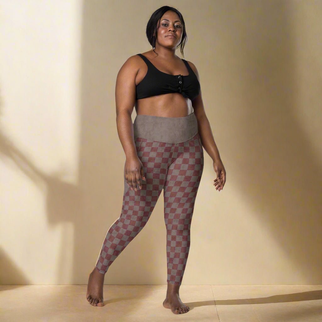 Woman wearing a black sports bra and checkered leggings on a neutral background
