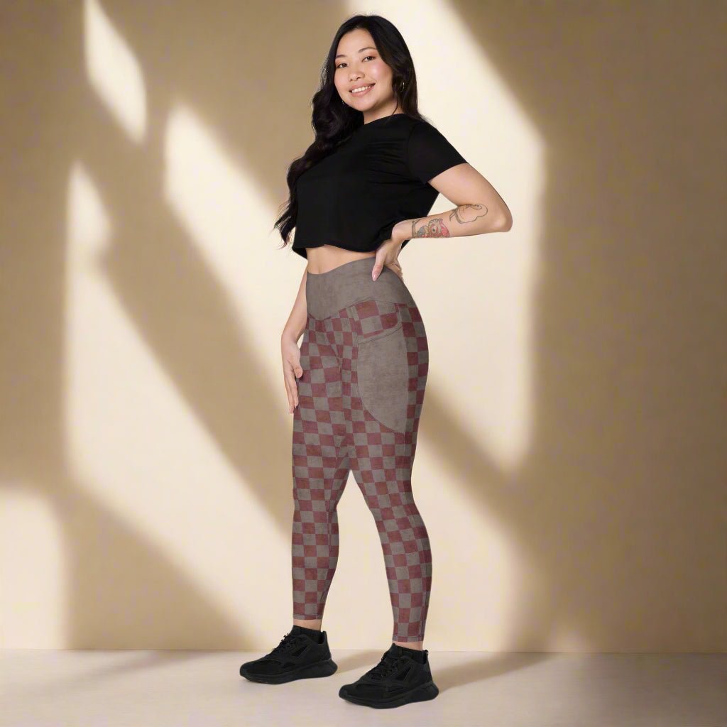 Woman wearing a black crop top and checkered leggings on a neutral background