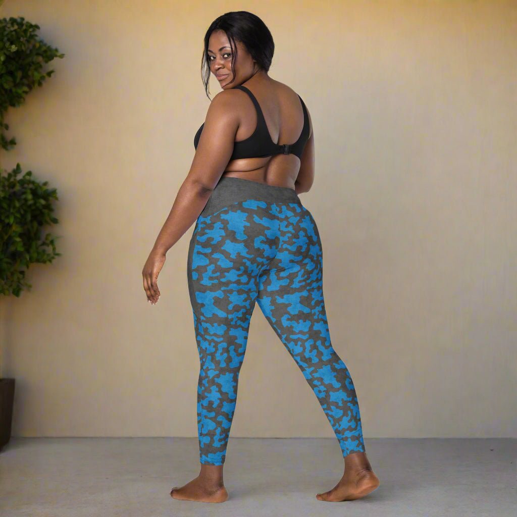 Woman wearing blue and gray camouflage leggings against a beige wall.