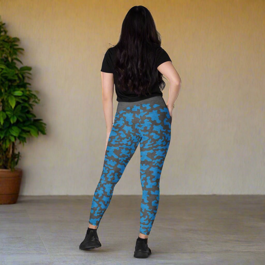 Person wearing blue camouflage leggings standing in a room with a plant.