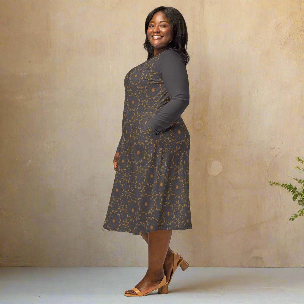 Woman wearing a patterned dress standing against a beige wall.