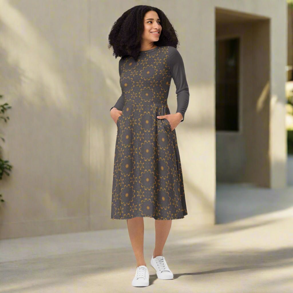 Woman wearing a patterned dress standing outdoors with a neutral background