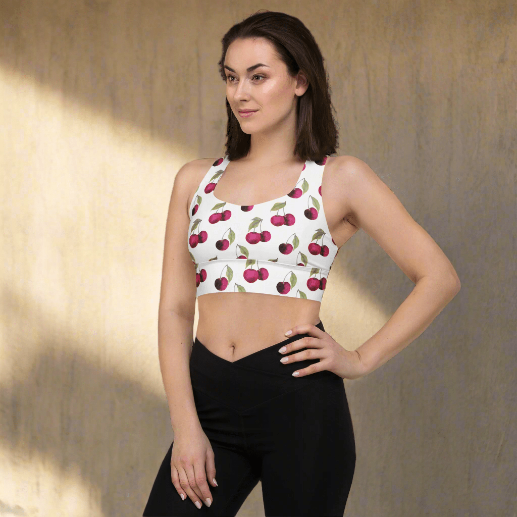 Woman wearing a sports bra with cherry pattern on a white background