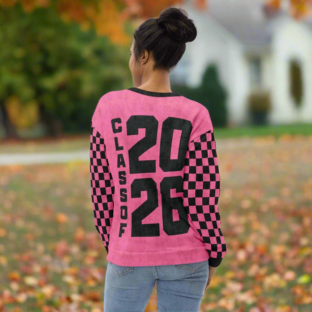 Person wearing a pink sweatshirt with 'Class of 2026' text outdoors