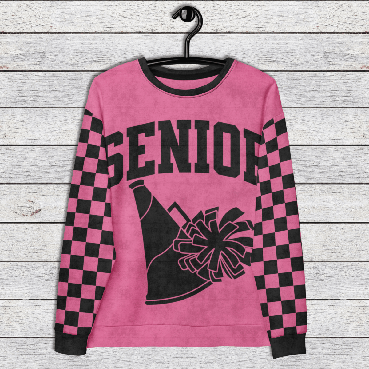 Pink sweatshirt with 'Senior' and cheerleading graphics on a wooden surface