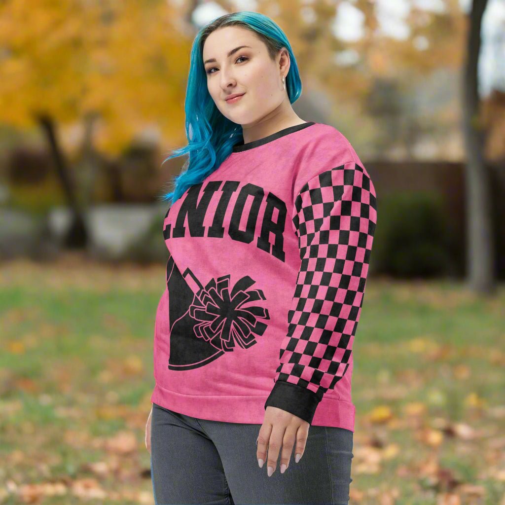 Person wearing a pink long-sleeve shirt with black checkered pattern and 'Senior' Cheerleader design.