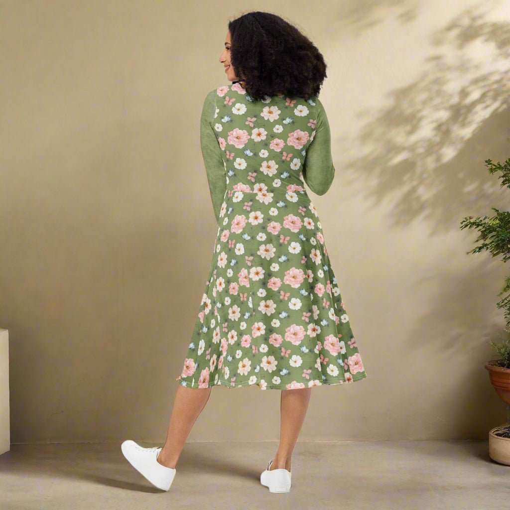 Woman wearing a green floral dress against a beige wall.