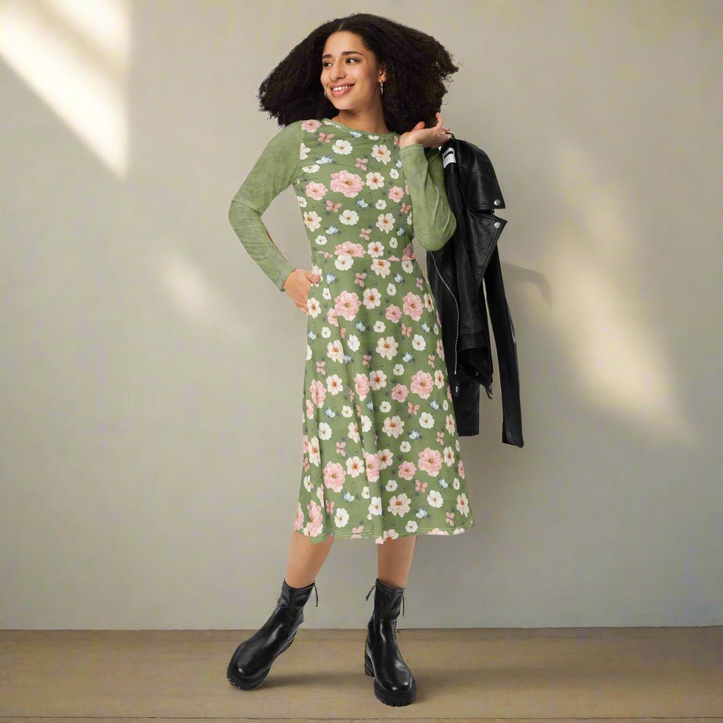 Woman wearing a green floral dress holding a black jacket on a neutral background