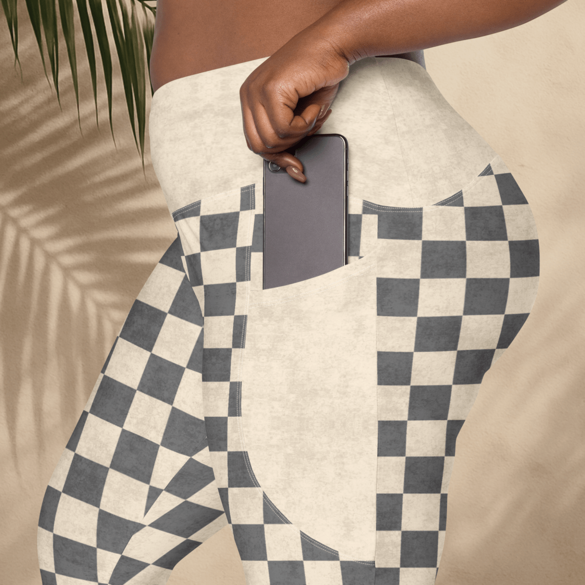 Person wearing checkered legging with a pocket, holding a phone.