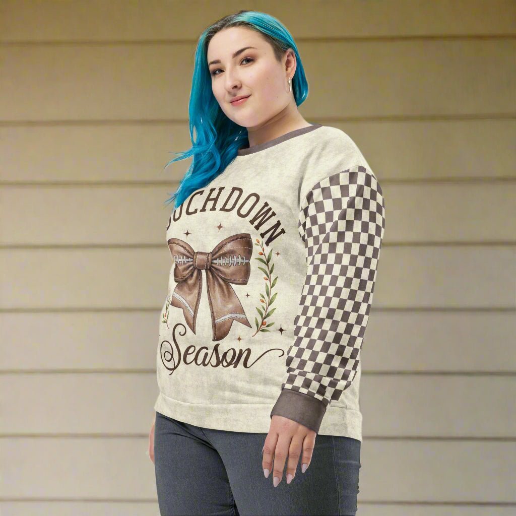 Person wearing a football sweater with a bow and text design against a beige wall.