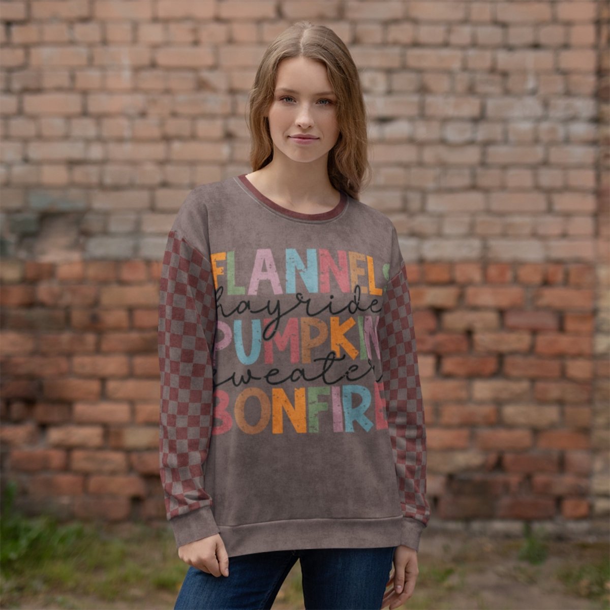 Woman wearing a burgundy and espresso sweatshirt with text in front of a brick wall