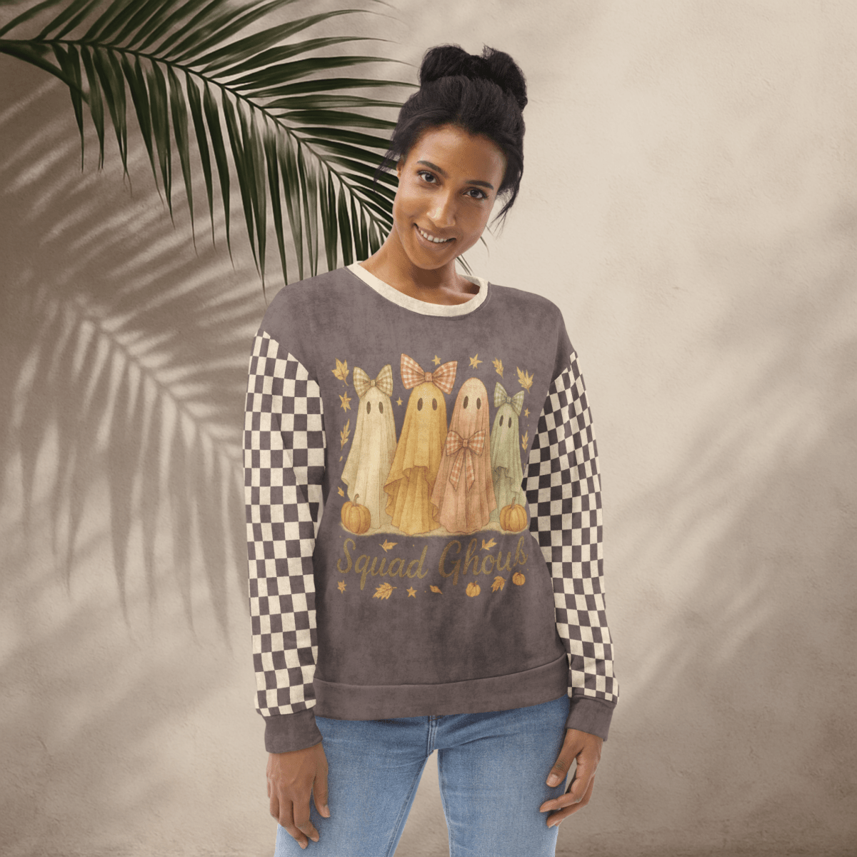 Woman wearing a sweater with ghost designs and checkered sleeves against a neutral background