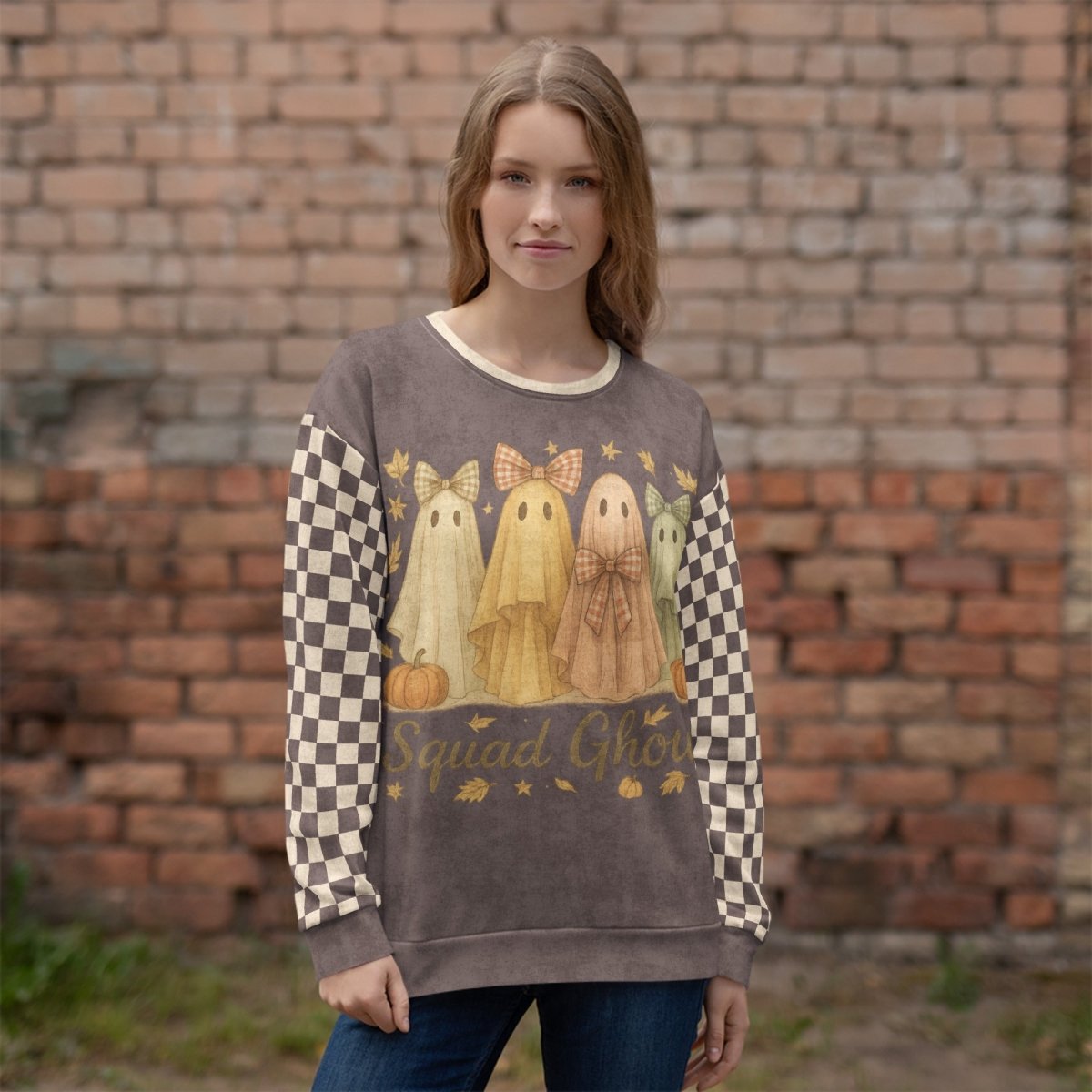 Woman wearing a sweater with ghost design and 'Squad Ghouls' text against a brick wall.