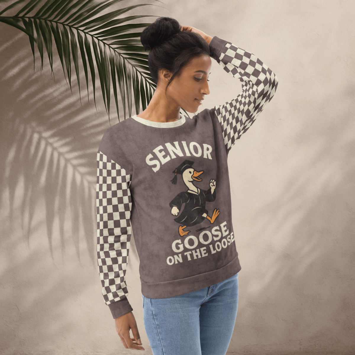 Woman wearing a sweater with 'Senior Goose on the Loose' design against a beige background