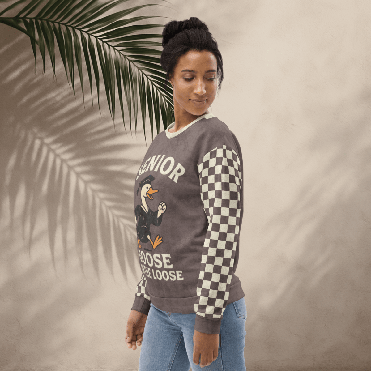 Woman wearing a sweater with 'Senior Goose on the Loose' design against a beige background