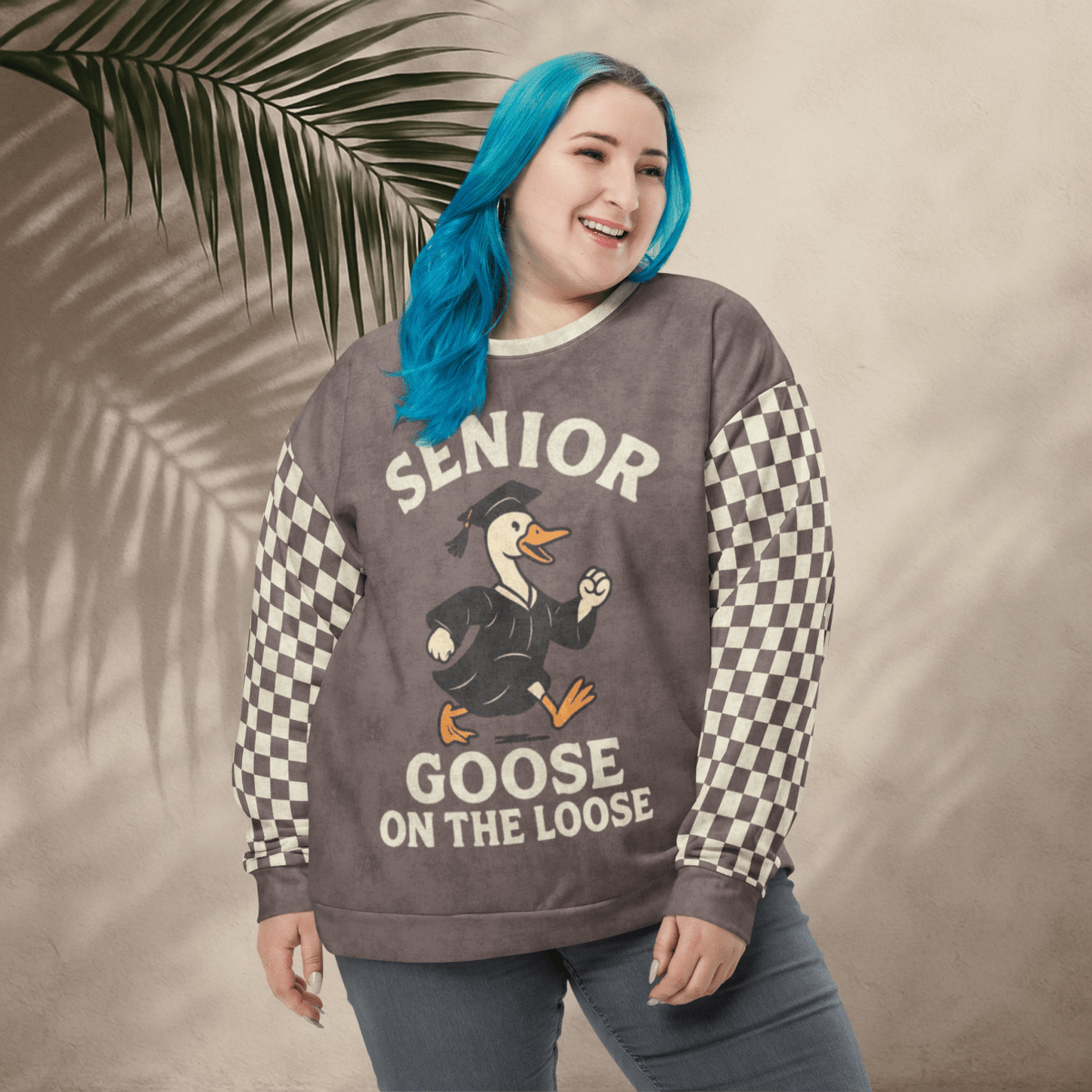 Woman wearing a sweater with 'Senior Goose on the Loose' design against a beige background