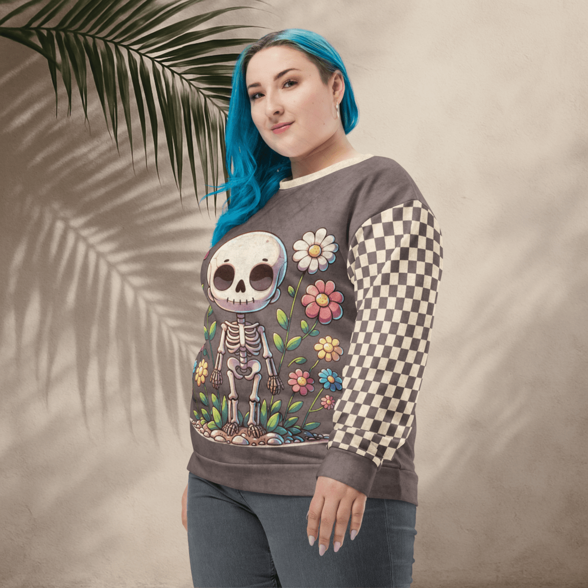 Person wearing a sweatshirt with a colorful skeleton design and checkered sleeves against a beige background.