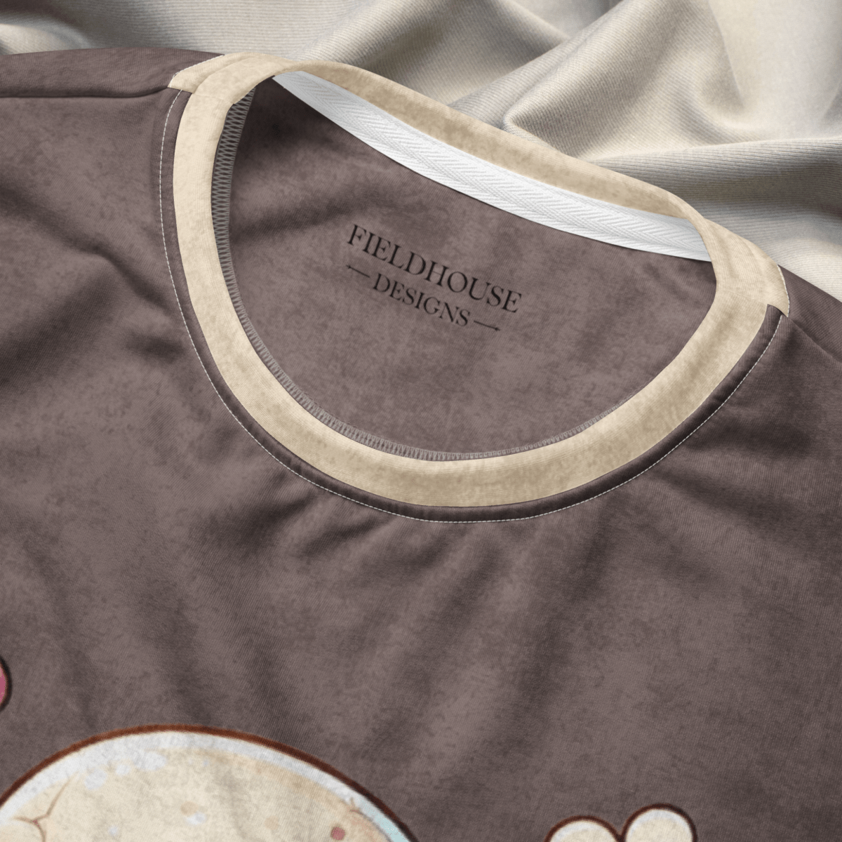 Close-up of a brown garment with 'Fieldhouse Designs' logo on a gay fabric background