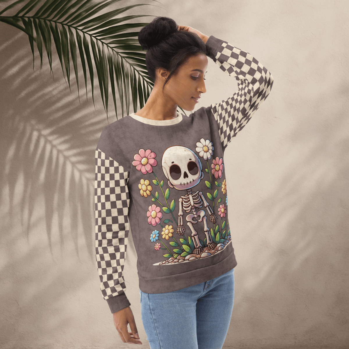 Woman wearing a sweater with a skeleton design and flowers against a neutral background