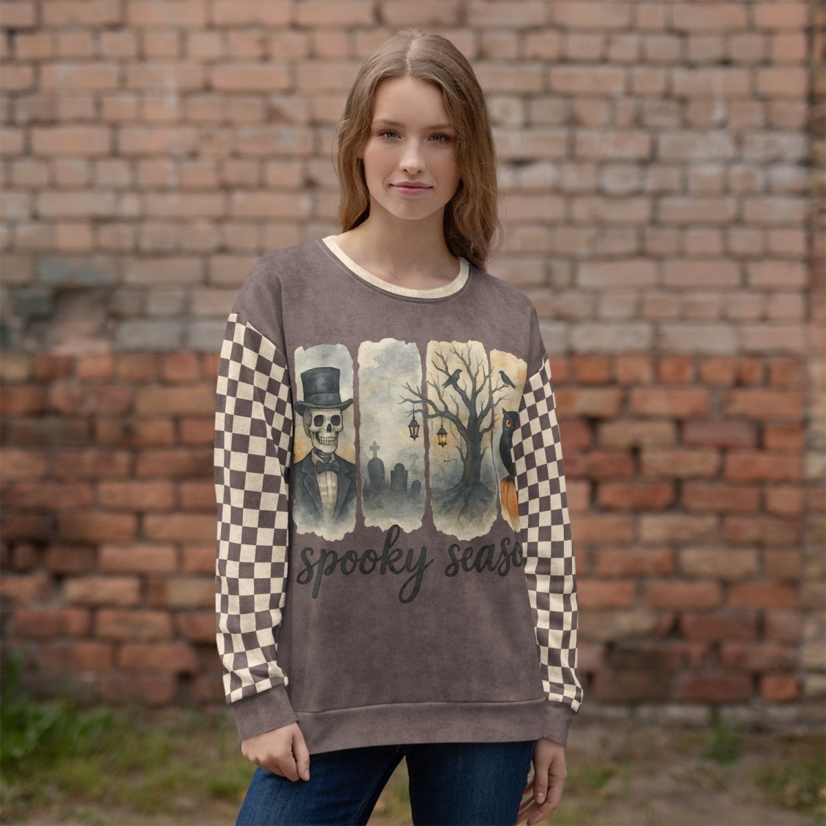 Woman wearing a sweater with 'spooky season' design against a brick wall.