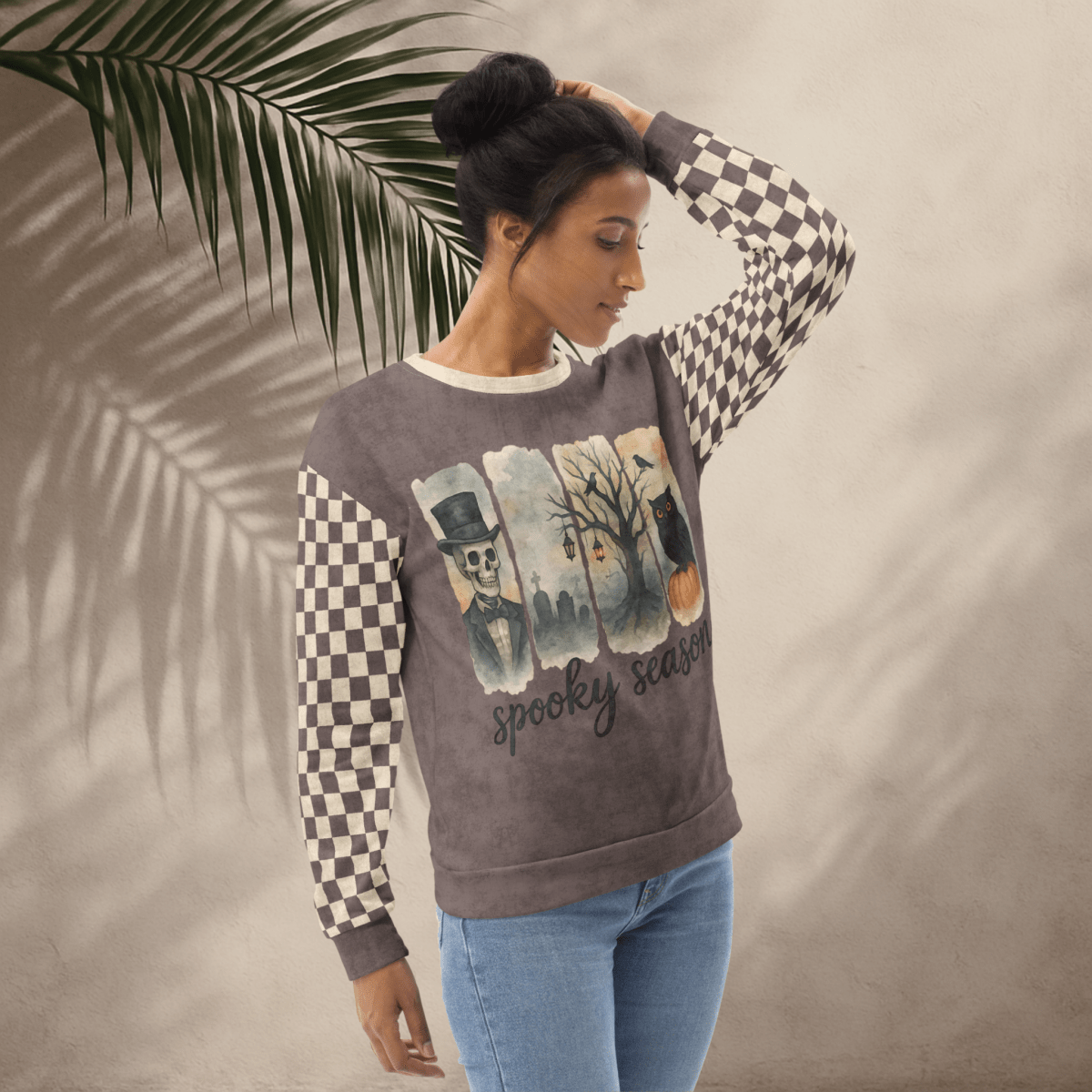 Woman wearing a sweater with a Halloween-themed design against a neutral background