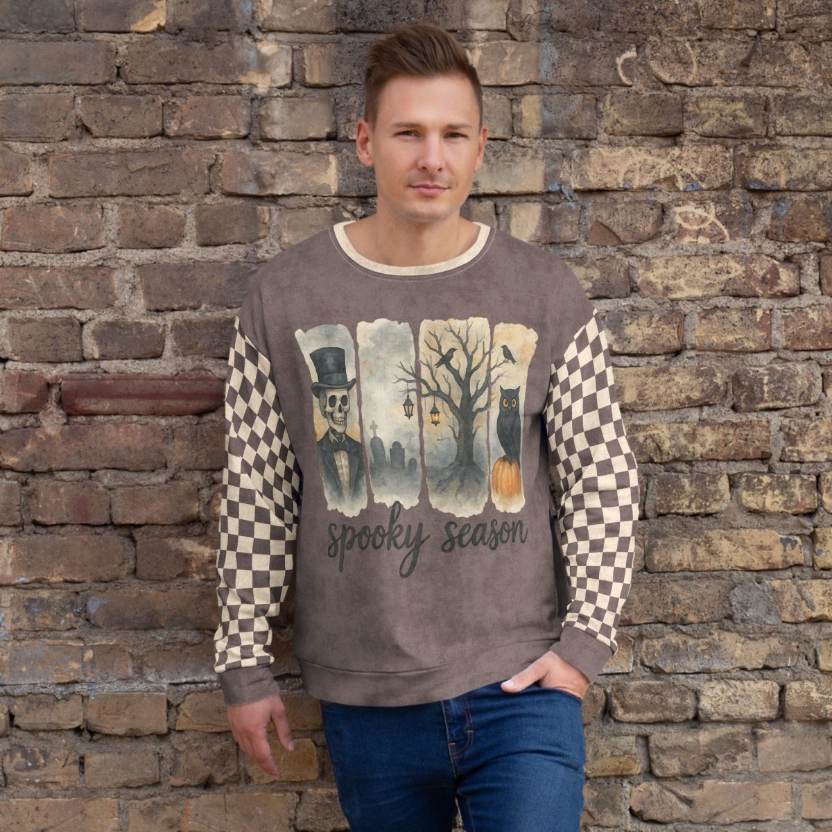 Man wearing a sweater with a 'Spooky Season' design against a stone wall.