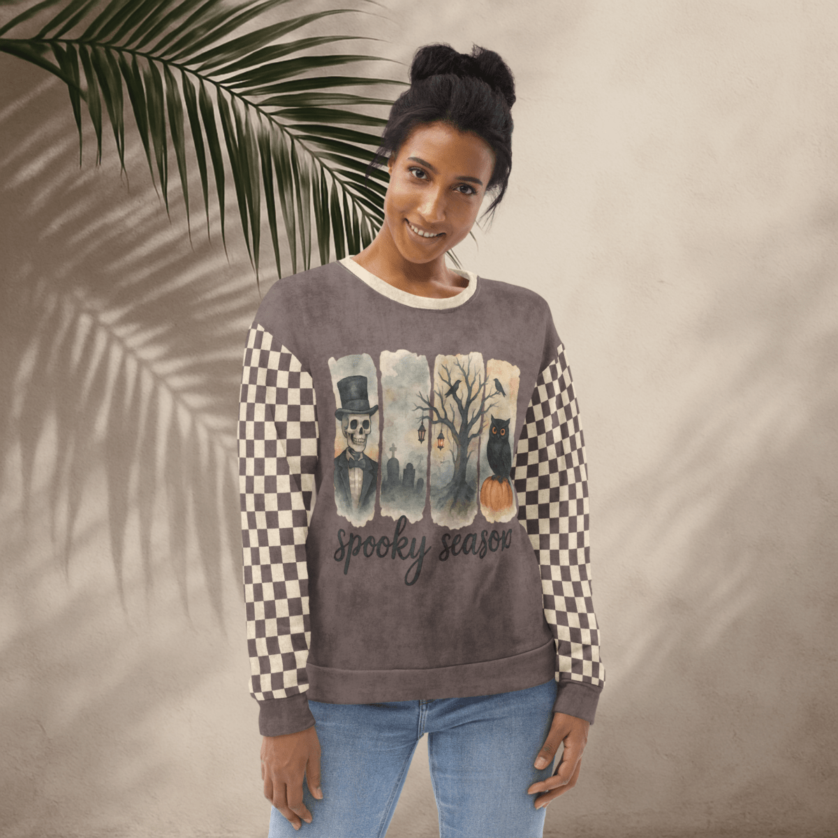 Woman wearing a sweater with checkered sleeves and 'Spooky Season' text against a neutral background