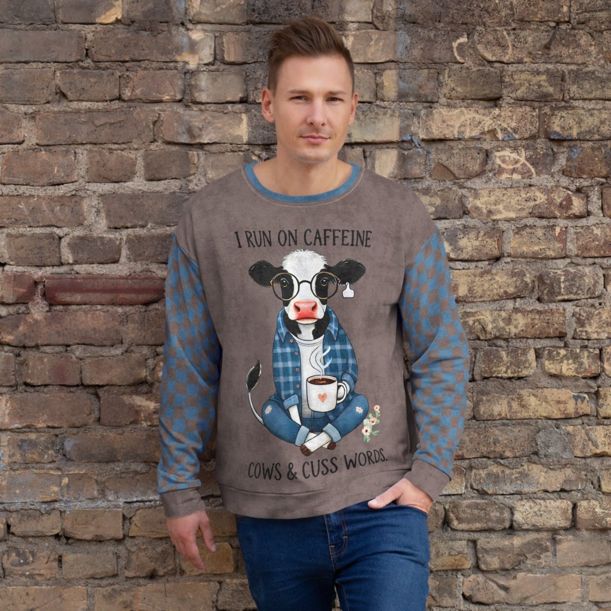 Man wearing Espresso and denim Sweatshirt with a cow graphic and text against a stone wall.
