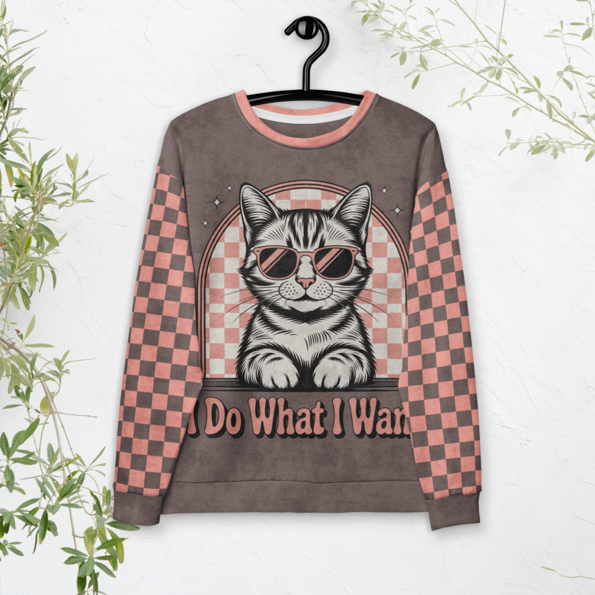 model wearing Espresso sweatshirt with a sunglasses-wearing tabby cat and “I Do What I Want” text; sleeves feature pink-and-espresso checkerboard pattern with pink collar and cuffs.