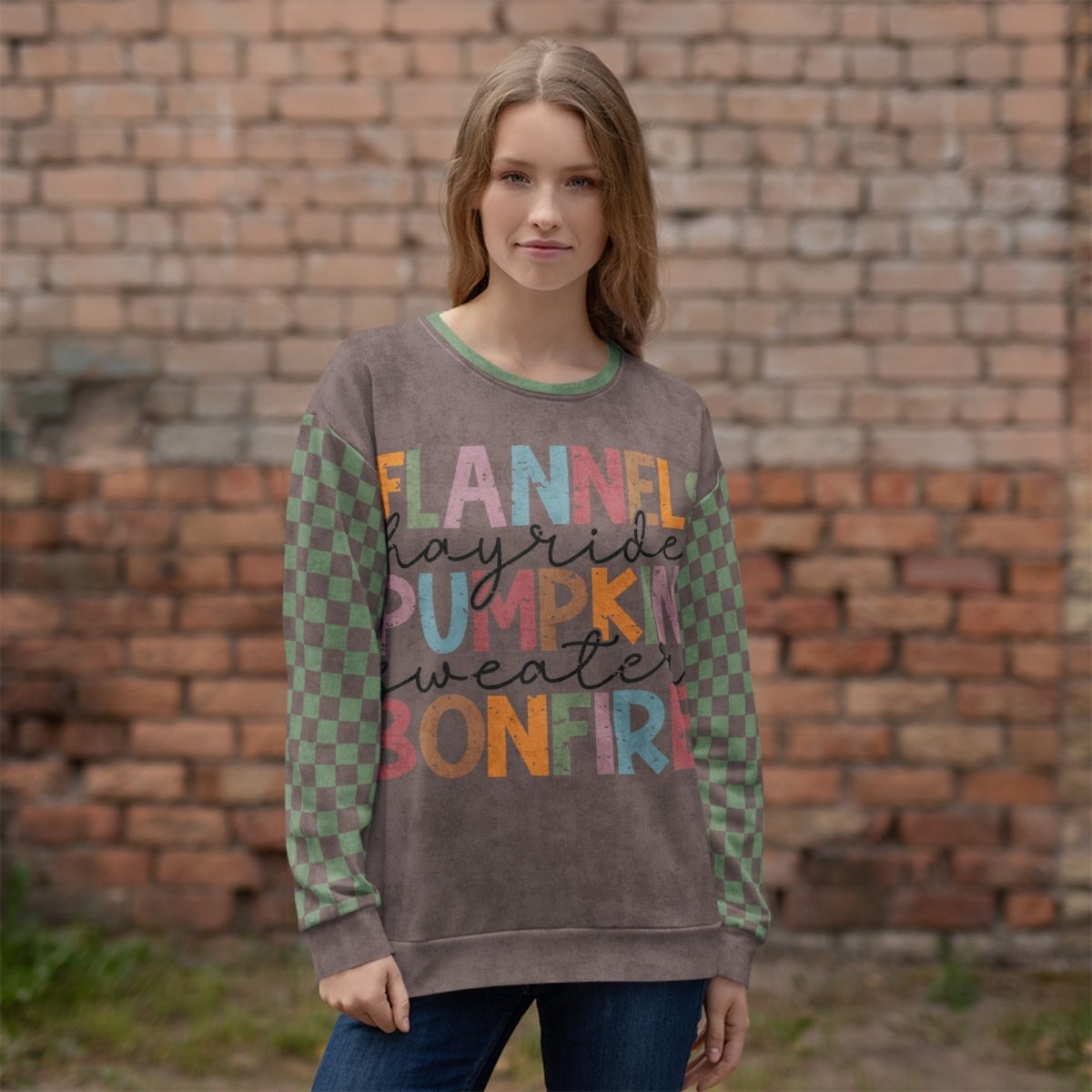Woman wearing an Espresso and sage green sweatshirt with colorful text in front of a brick wall