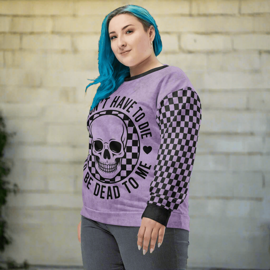 Person wearing a purple sweatshirt with a skull design and text, standing against a brick wall.