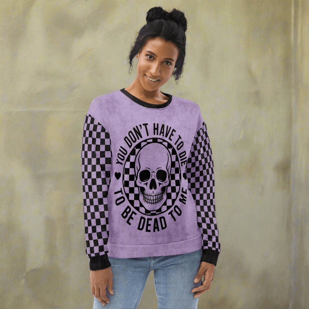 Person wearing a purple sweatshirt with a skull design and text on a neutral background