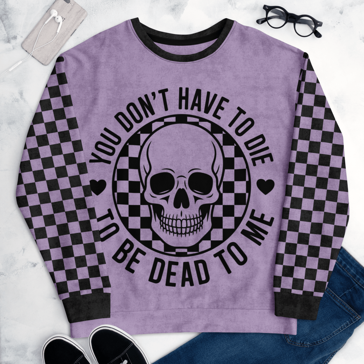 Purple sweatshirt with skull design and text on a marble surface