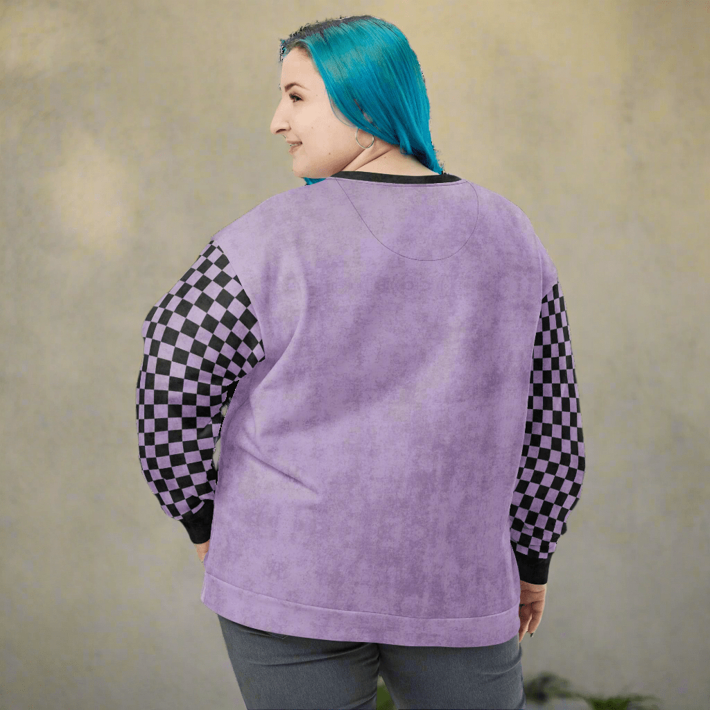 Person wearing a purple sweatshirt with checkered sleeves against a beige background