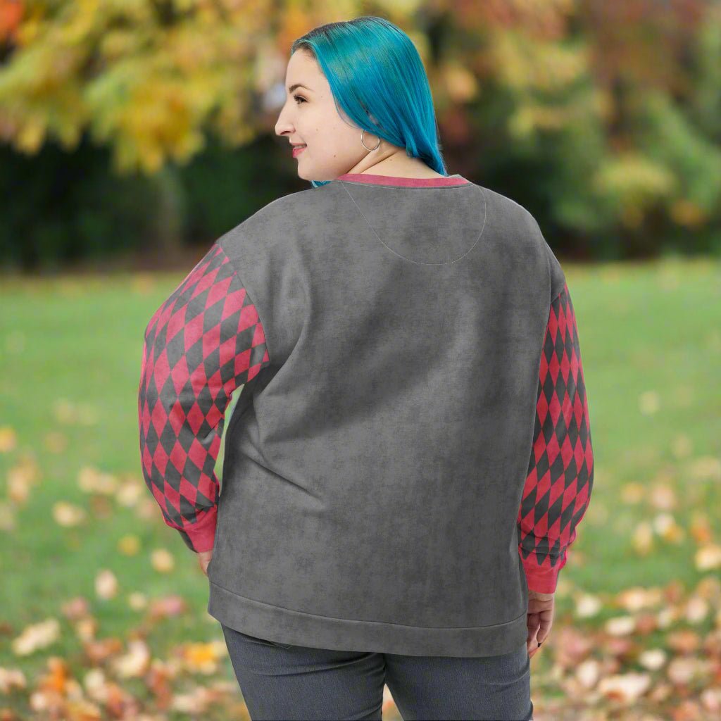 Person wearing a gray sweatshirt with red and black patterned sleeves outdoors